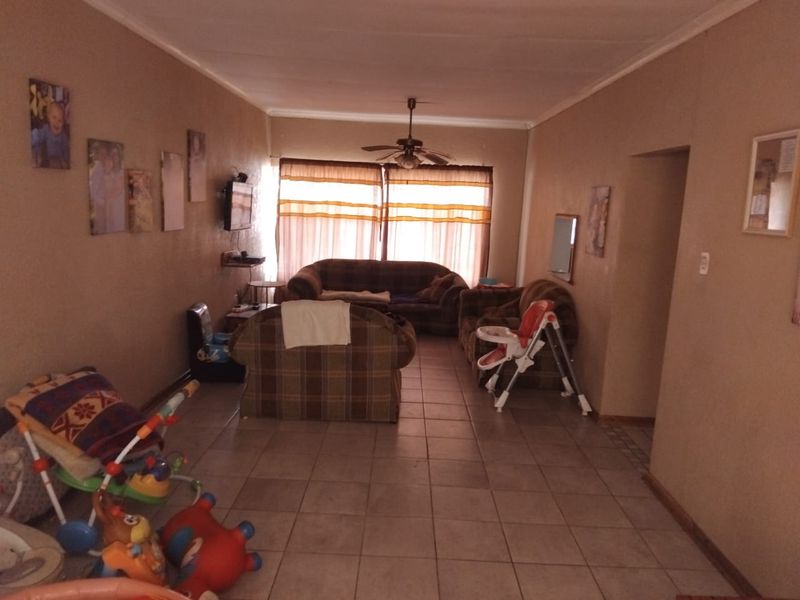 A spacious living room featuring tiled flooring and a ceiling fan, offering a functional layout with natural light from the window.