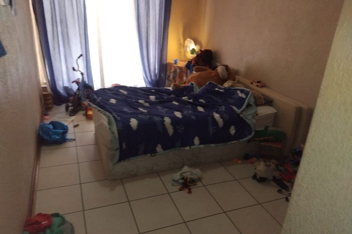 A bedroom featuring tiled flooring and access to a balcony through a sliding glass door, requiring cosmetic updates to improve its overall appeal.
