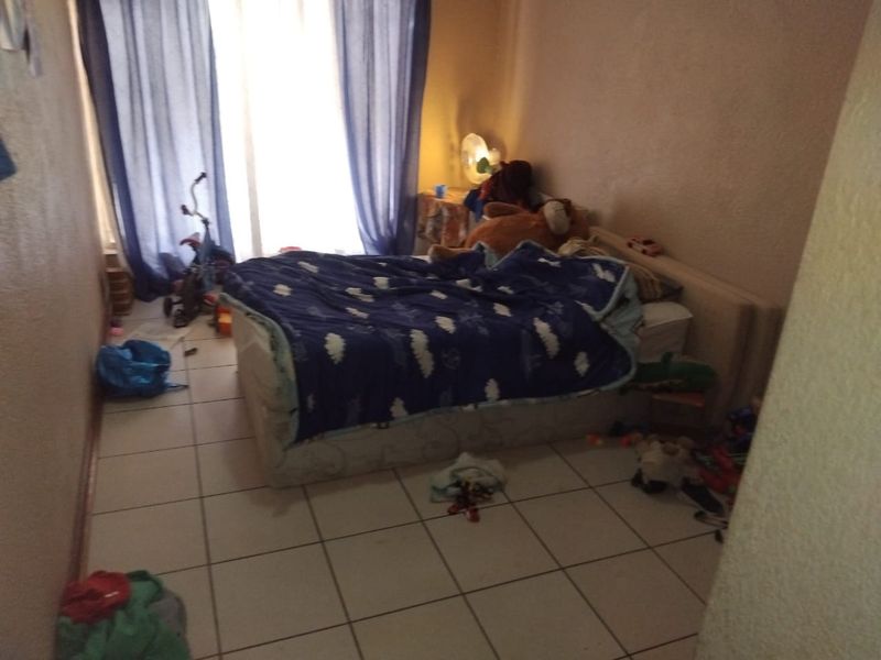 A bedroom featuring tiled flooring and access to a balcony through a sliding glass door, requiring cosmetic updates to improve its overall appeal.
