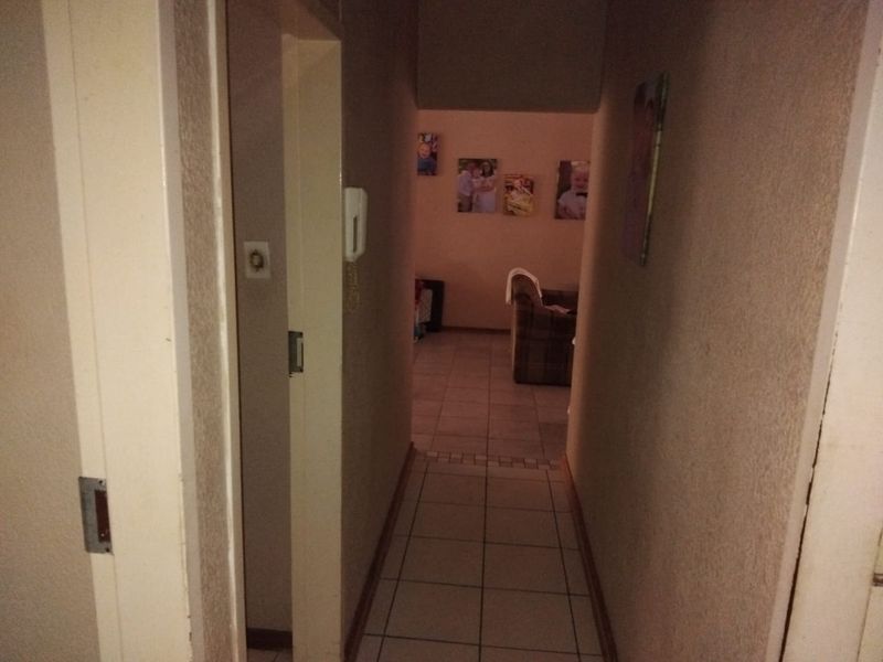 A functional hallway featuring tiled flooring and a wall-mounted intercom system, providing access to the living area.