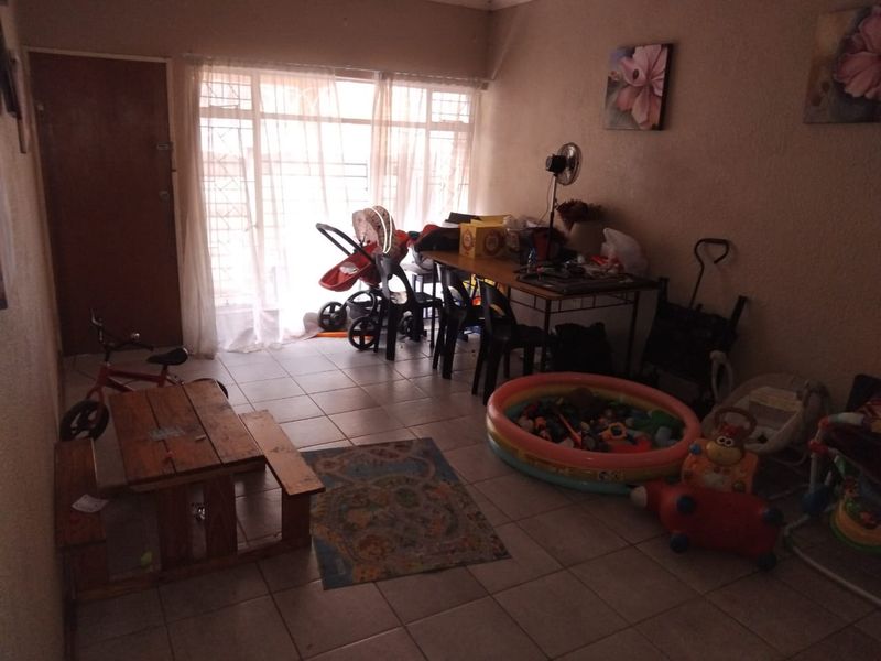 A living area featuring tiled flooring and a sliding door with security gate, providing access to the exterior.