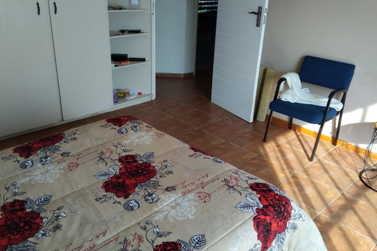 A bedroom featuring tiled flooring and built-in wardrobe storage, offering a functional space with neutral wall finishes.
