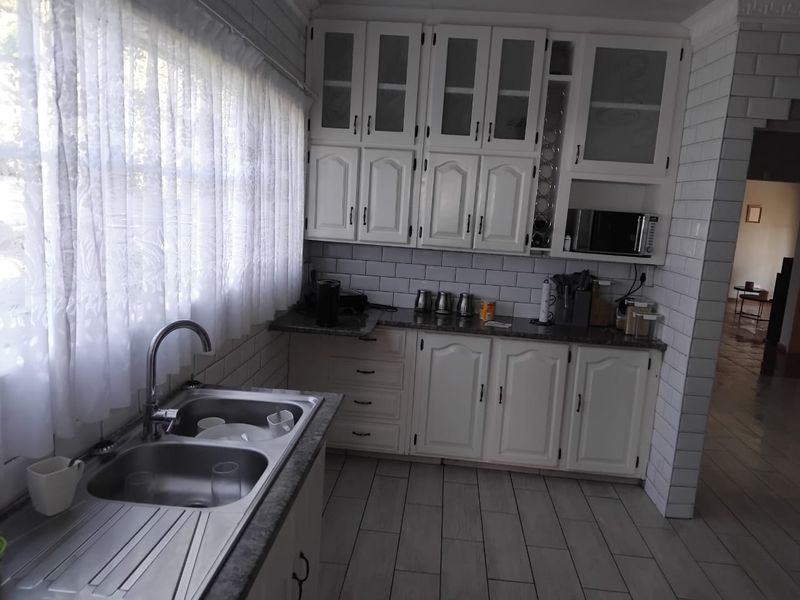 A functional kitchen featuring white cabinetry, subway tile backsplash, laminate countertops, and a double bowl stainless steel sink with a modern mixer tap.