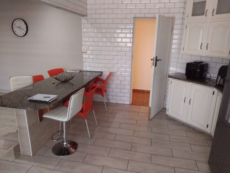 A functional kitchen area featuring a granite-topped breakfast bar, white subway tile backsplash, and classic cabinetry with tiled flooring.
