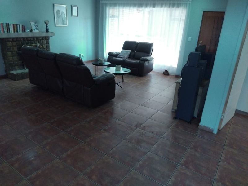A living room featuring tiled flooring and a stone fireplace, with natural light entering through a large sliding glass door.