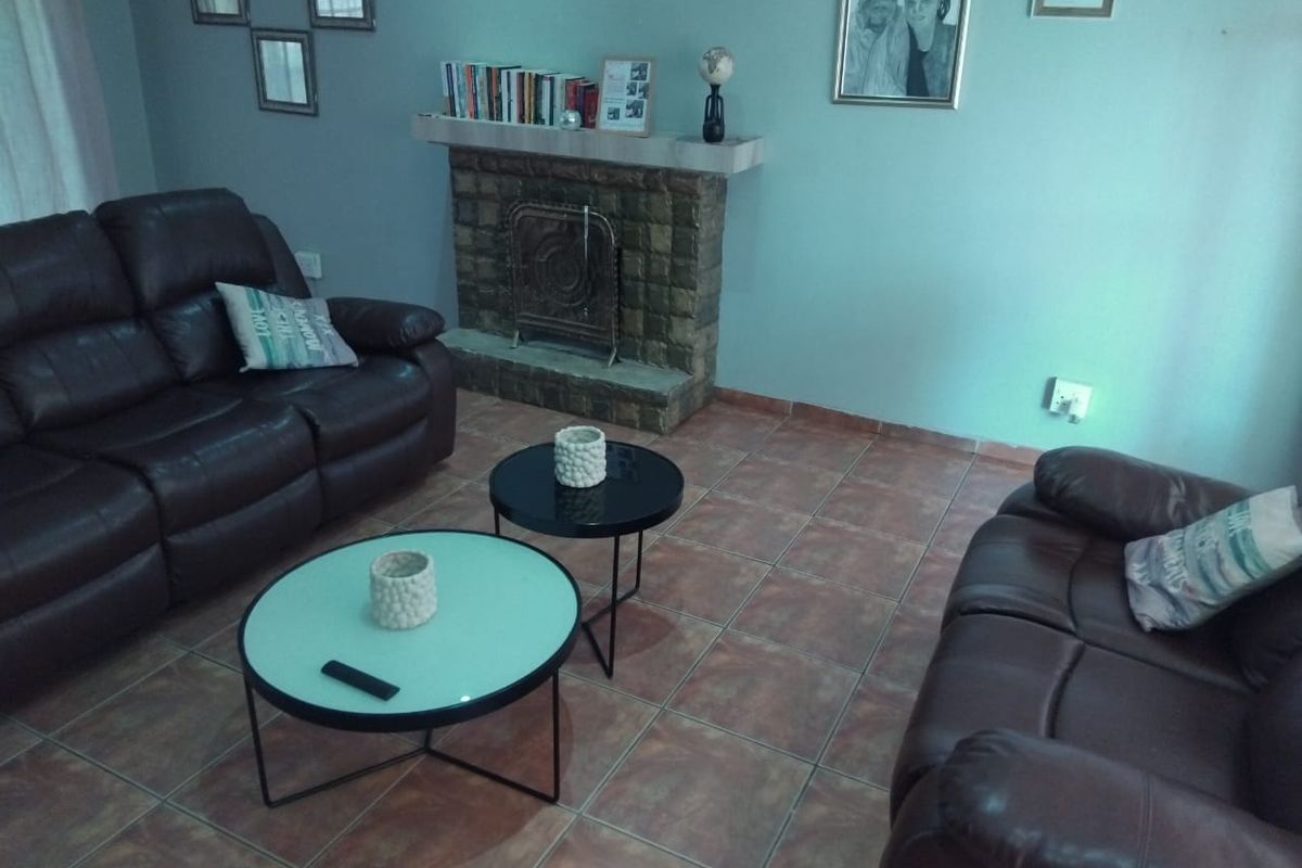 A living room featuring a stone fireplace and tiled flooring.