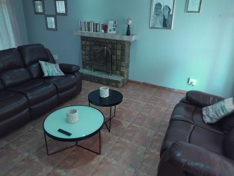 A living room featuring a stone fireplace and tiled flooring.