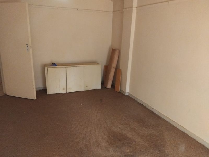 An empty bedroom featuring worn carpet flooring and plain walls, offering a blank canvas for renovation or interior design updates.
