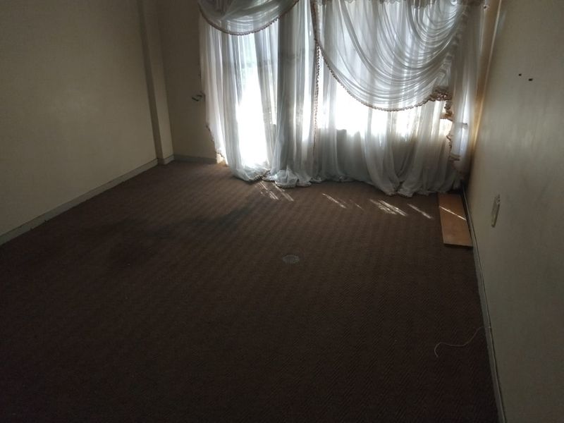 An empty bedroom featuring worn, stained carpeting and neutral walls, awaiting renovation or new flooring to refresh the space.