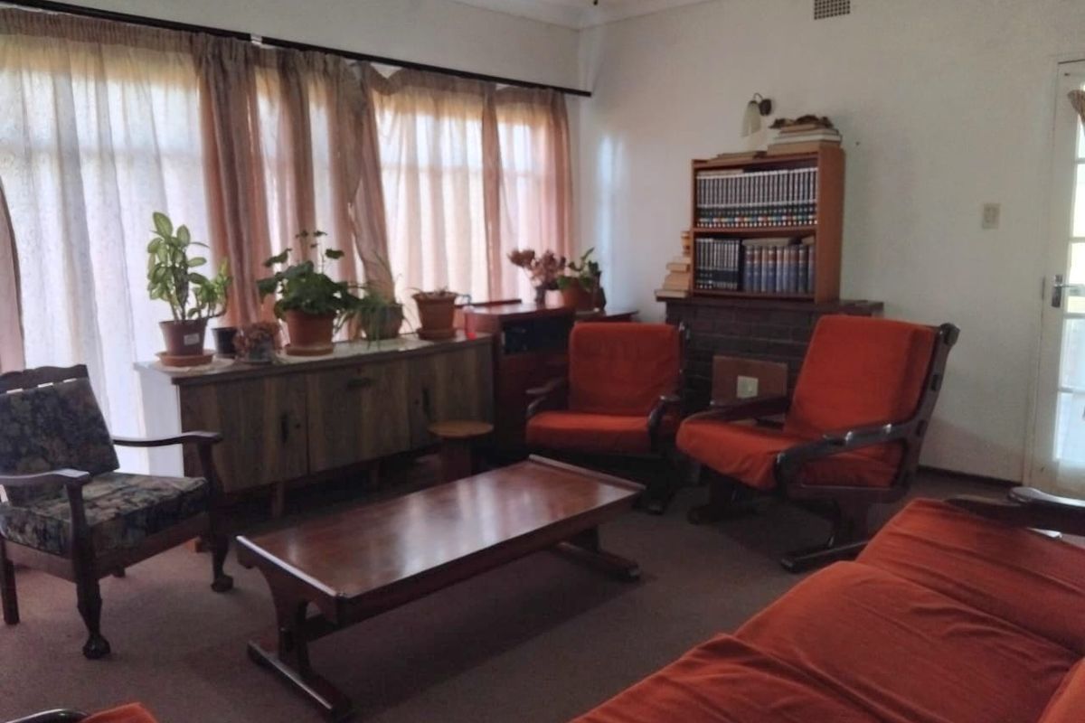 A traditional living room featuring a brick fireplace, carpeted flooring, and large windows that provide ample natural light.