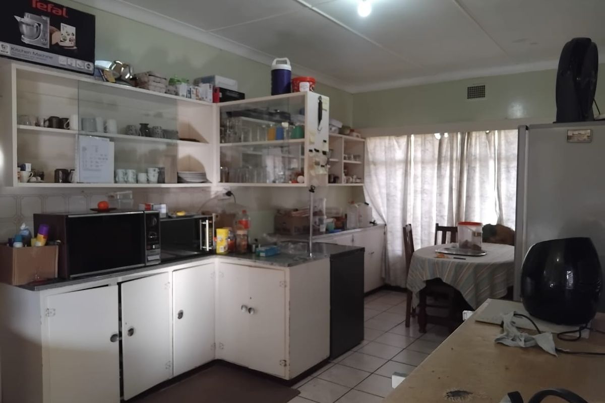A functional kitchen featuring white cabinetry, tiled flooring, and open shelving, offering a practical layout with potential for modern updates.