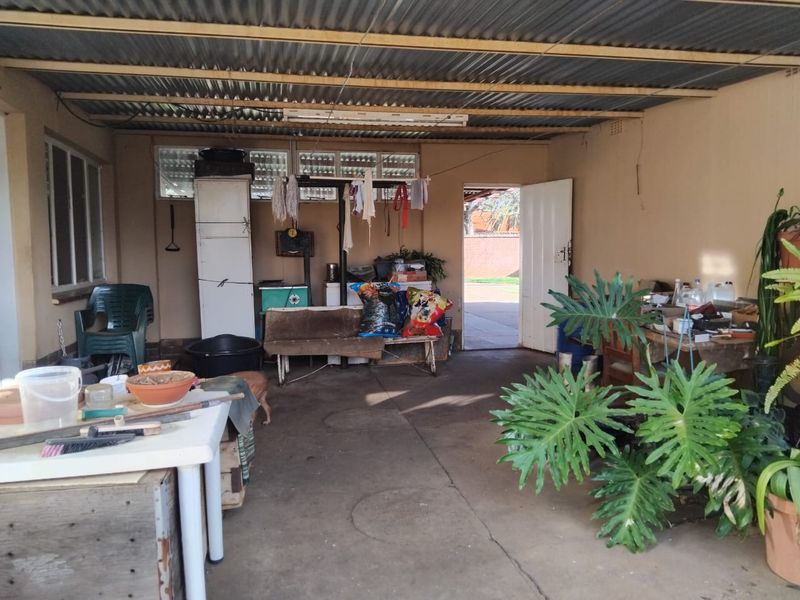 A functional garage space featuring a corrugated metal roof, concrete flooring, and natural light access through casement windows.