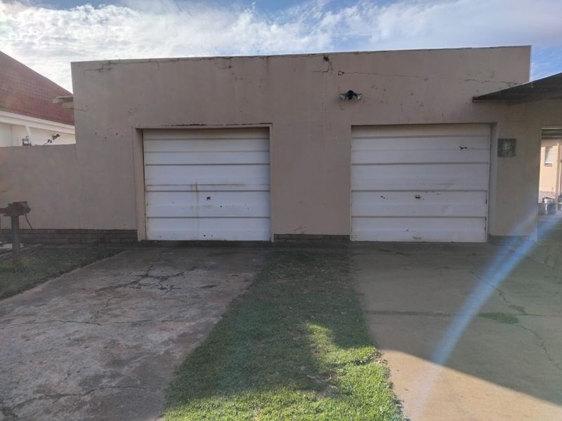 A detached double garage featuring concrete driveway access and visible wear to the exterior walls and garage doors.