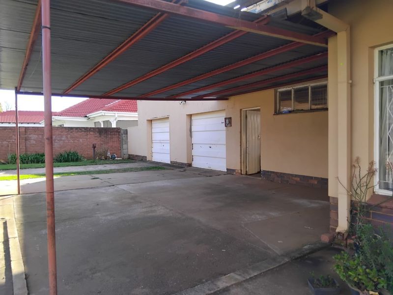 Exterior view of a double garage with an attached corrugated metal carport and concrete driveway area.