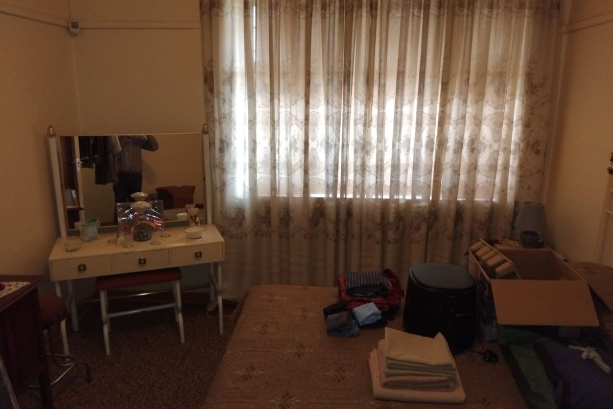 A bedroom featuring a window with curtains and a picture rail, requiring cosmetic updates to modernize the space.