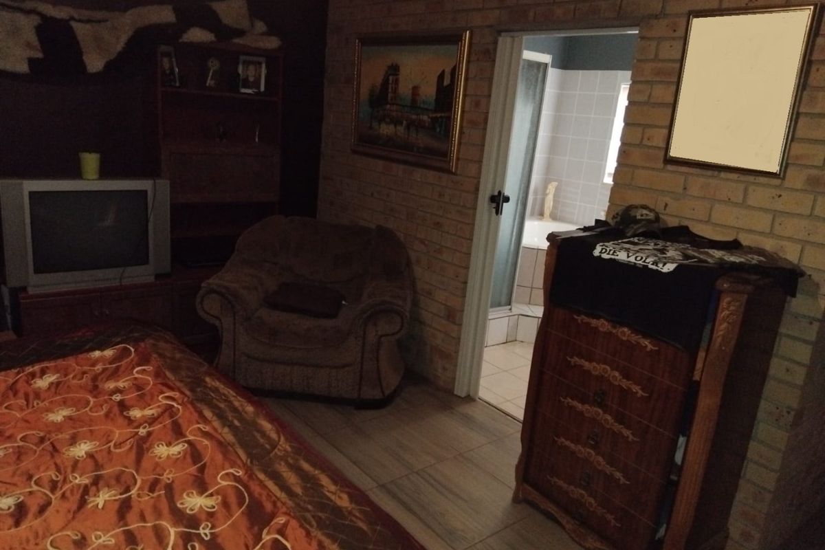 Bedroom featuring exposed brick walls and tiled flooring, with direct access to an en-suite bathroom.