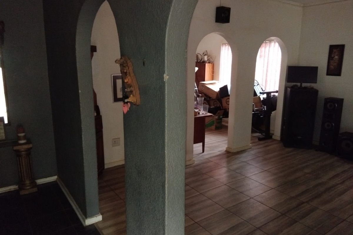 A living area featuring distinctive arched doorways and tiled flooring, providing a unique architectural layout with potential for modern interior updates.