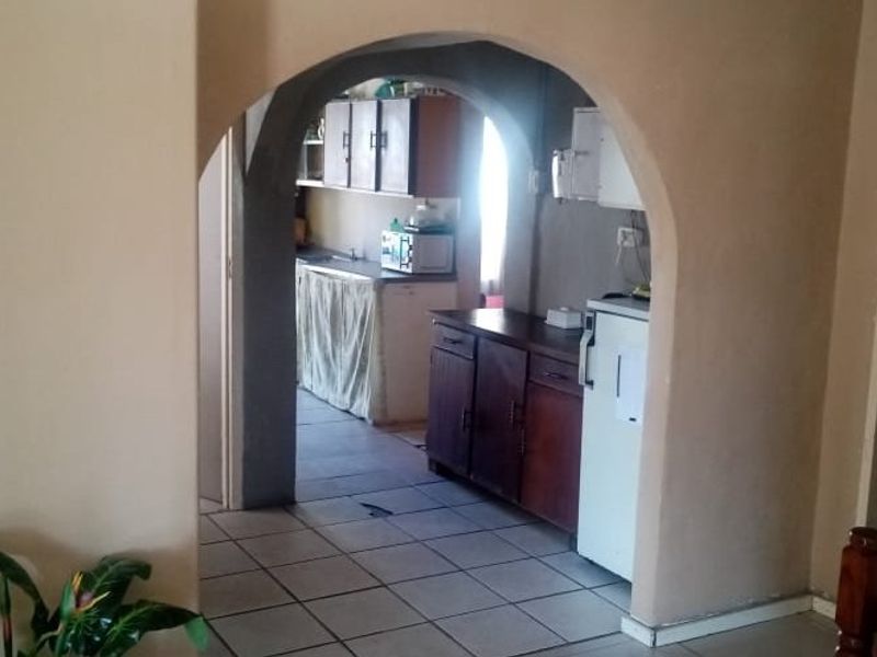 A view through an arched doorway into a functional kitchen featuring tiled flooring and built-in cabinetry.