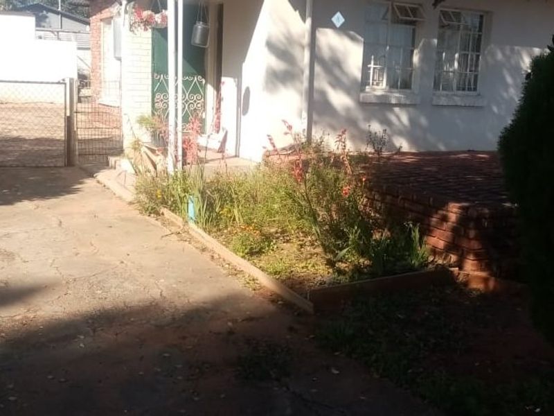 Front exterior view of the property featuring a concrete driveway, brick planter, and security gate entrance.