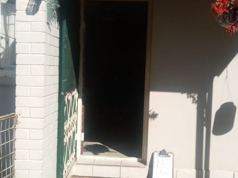 Front entrance area featuring a security gate and brick pillar detail, providing access to the main dwelling.