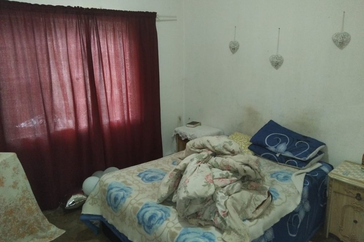 A bedroom featuring a window with curtain rod and visible wall surface wear requiring maintenance and cosmetic updates.