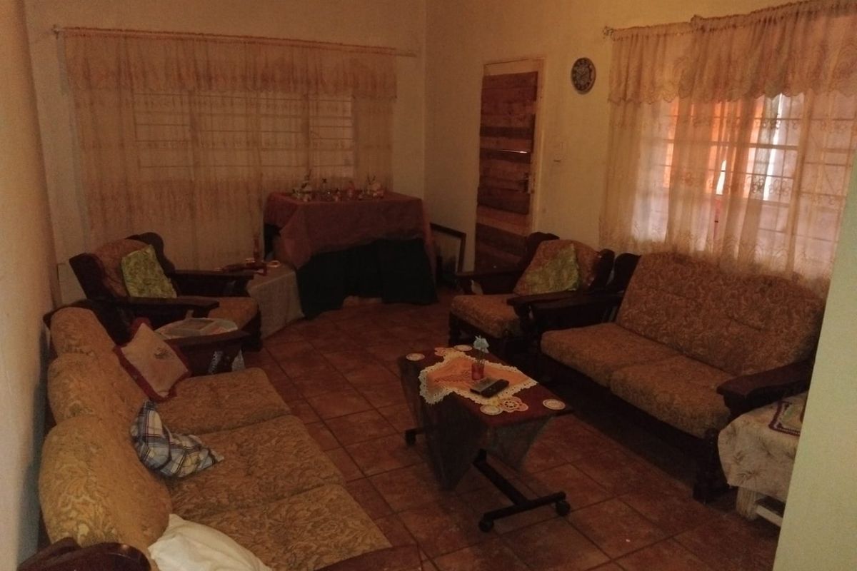 A dated living room featuring tiled flooring and traditional window treatments, offering a blank canvas for modern interior updates.