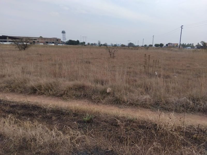 A view of a vacant residential plot featuring dry grass and utility infrastructure, suitable for future development.