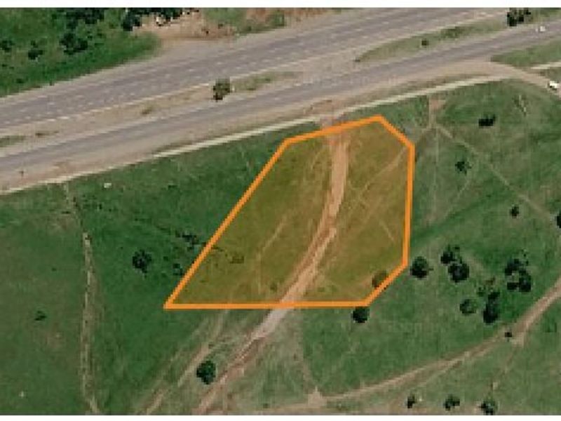 Aerial view of a vacant residential land plot with clear boundary markings, situated near major road infrastructure.