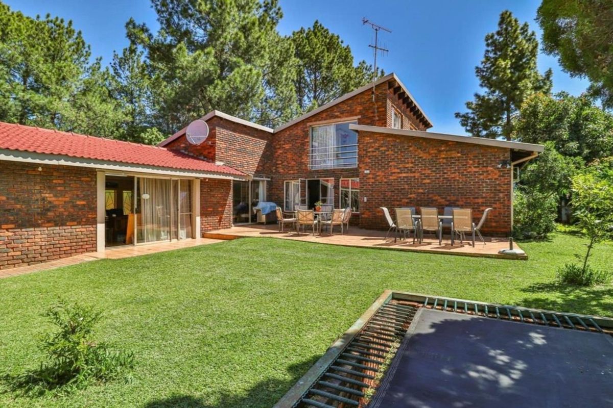 Rear view of a brick house featuring a wooden deck, sliding glass doors, and a spacious garden area.