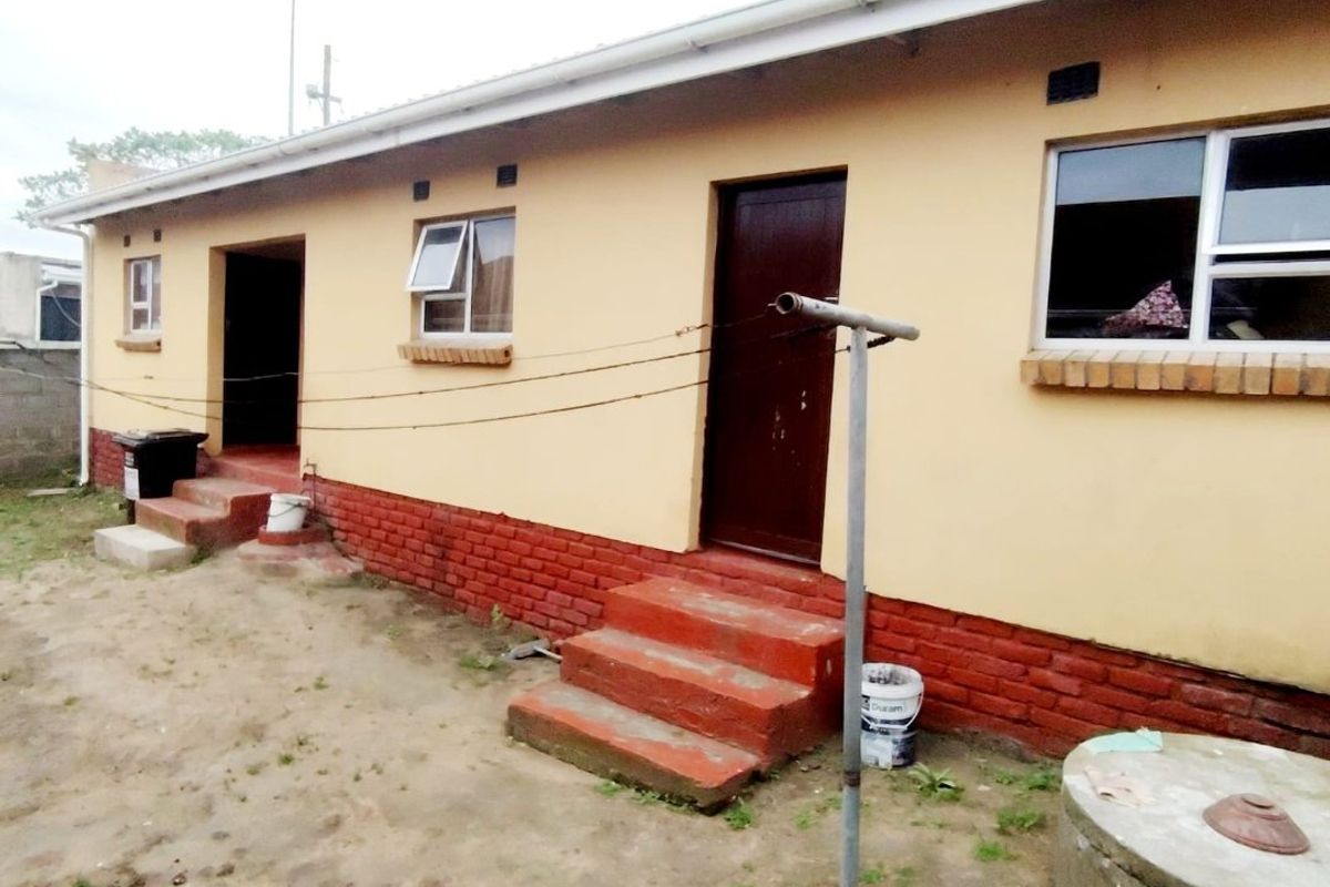 Rear exterior view of the house featuring brick base, concrete steps, and aluminium window frames.
