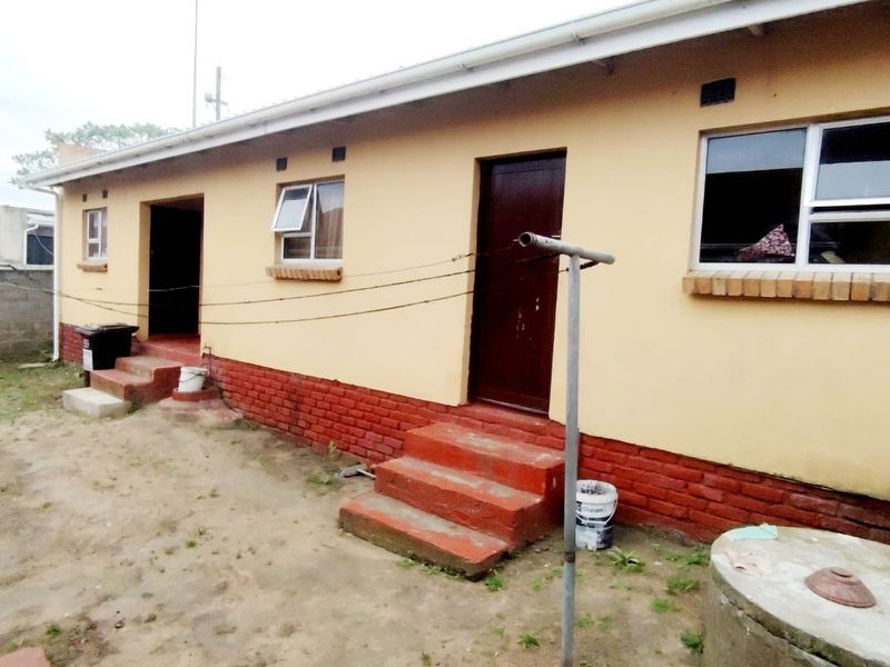 Rear exterior view of the house featuring brick base, concrete steps, and aluminium window frames.