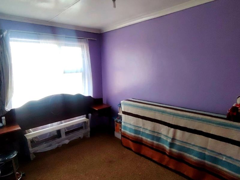 A bedroom featuring purple walls, carpet flooring, and a coved ceiling, offering a blank canvas for potential interior updates and modernization.