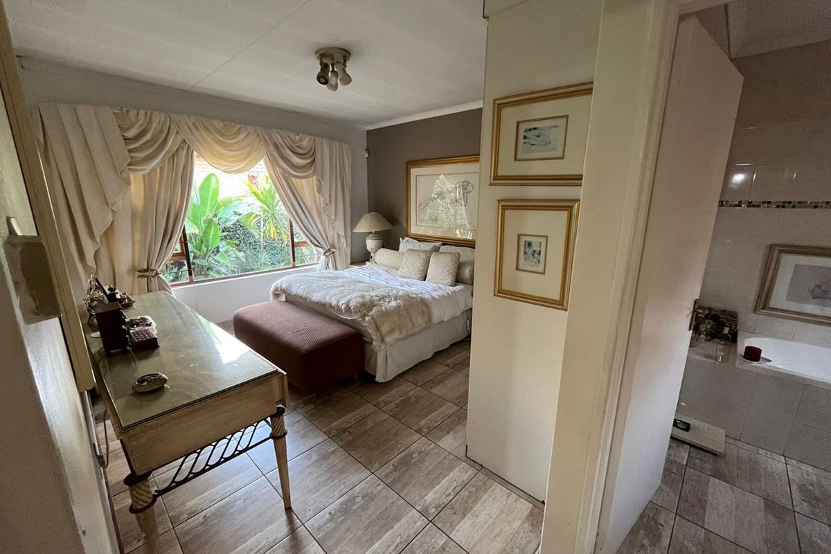 Spacious bedroom featuring tiled flooring and an en-suite bathroom area with a built-in bathtub, offering a functional layout with natural light.