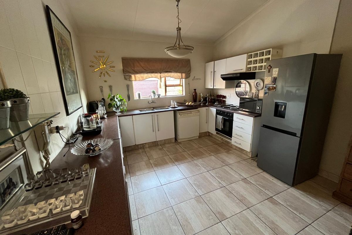 A functional kitchen featuring tiled flooring, ample built-in cabinetry, laminate countertops, a double basin sink, and integrated cooking appliances.
