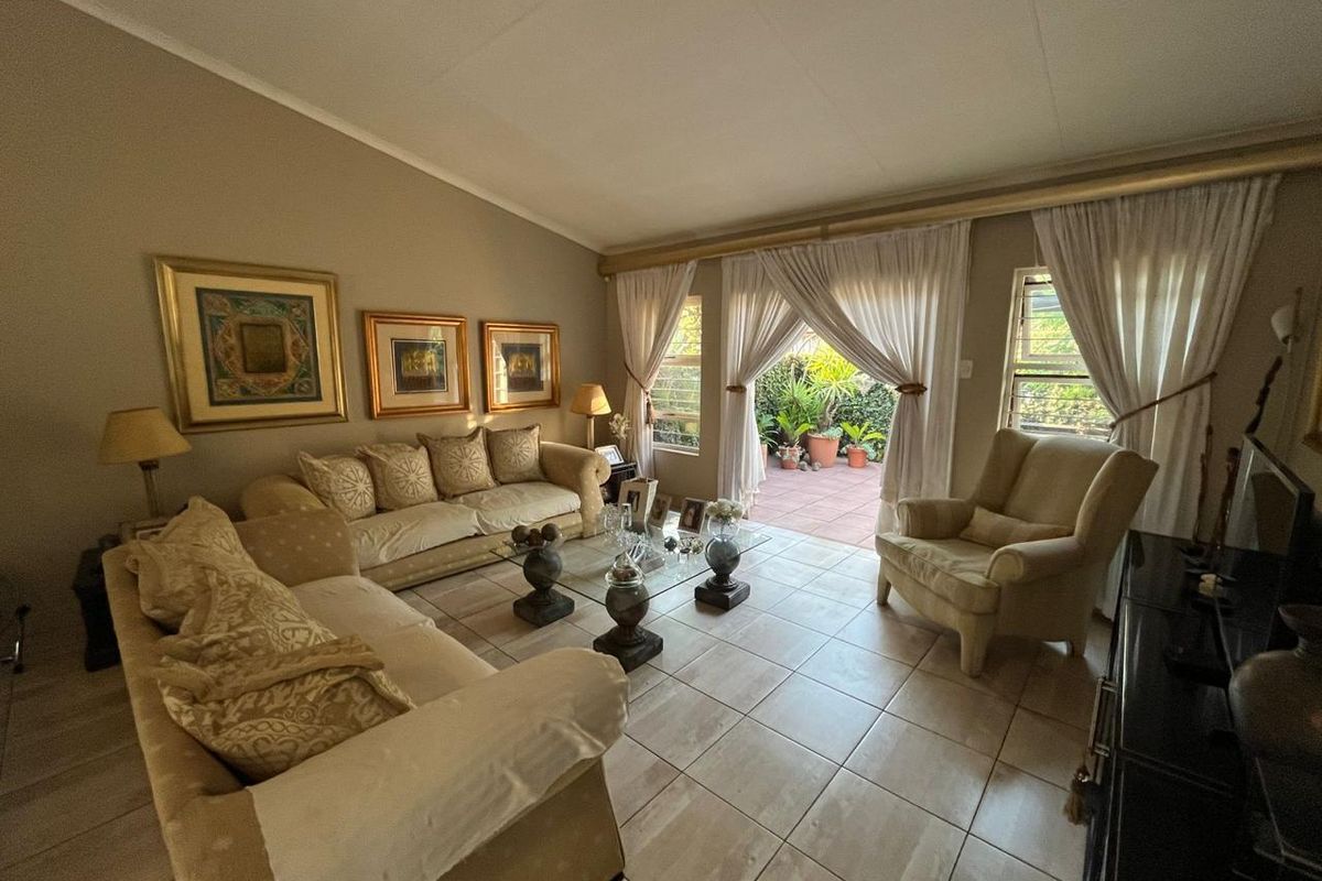 Spacious living room featuring tiled flooring, vaulted ceilings, and large sliding glass doors providing direct access to the outdoor patio area.
