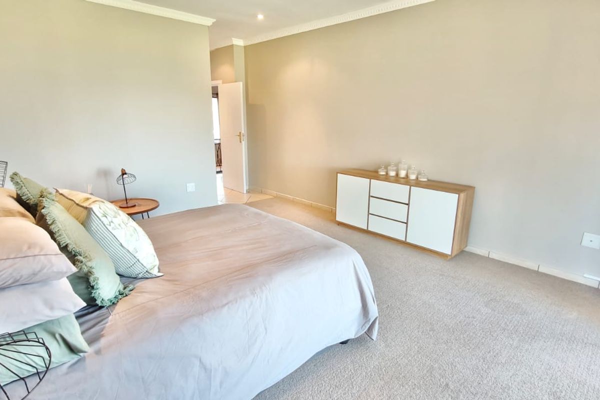 A spacious bedroom featuring neutral wall tones, carpeted flooring, and decorative coving, providing a comfortable and well-maintained living space.