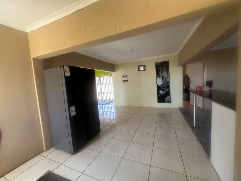 Open plan living area featuring tiled flooring and a breakfast bar, with a visible structural crack in the ceiling beam.