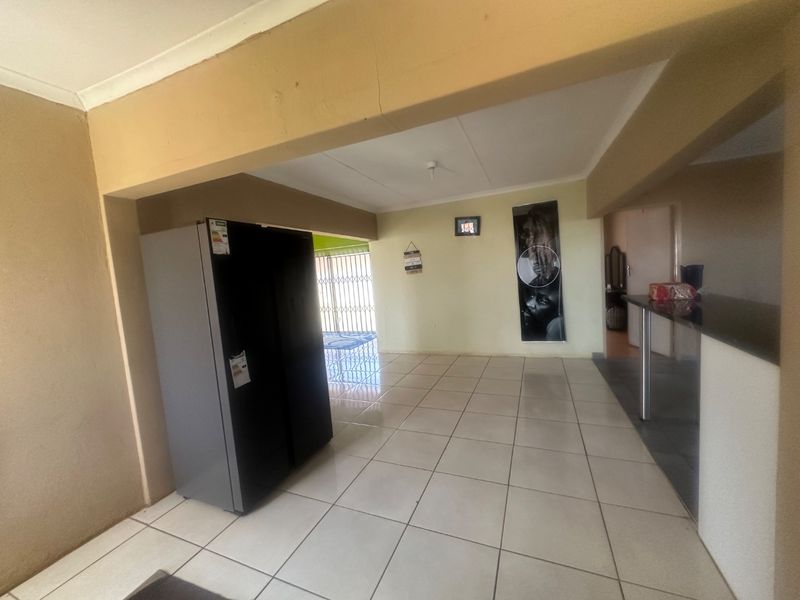 Open plan living area featuring tiled flooring and a breakfast bar, with direct access to an exterior security gate.