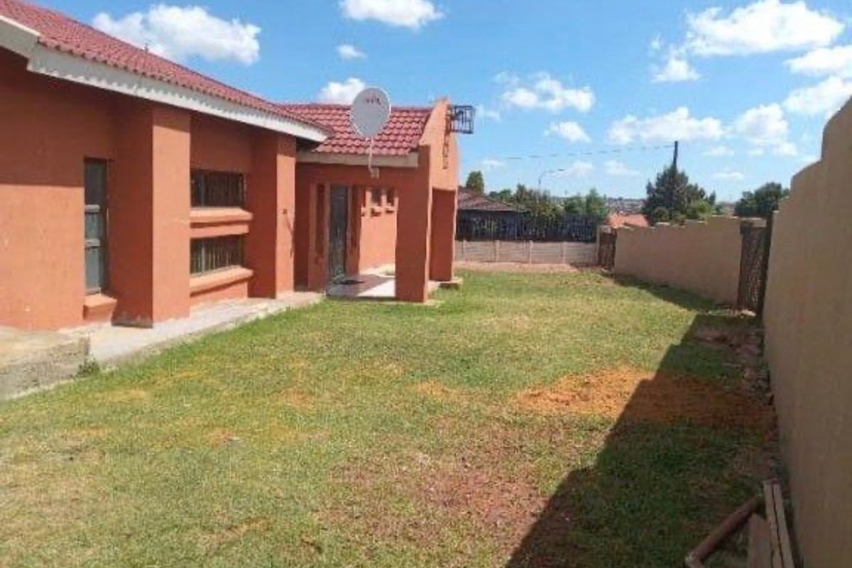 Rear view of the house featuring a tiled roof, satellite dish, and a private garden area enclosed by boundary walls.