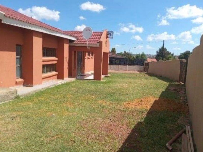 Rear view of the house featuring a tiled roof, satellite dish, and a private garden area enclosed by boundary walls.
