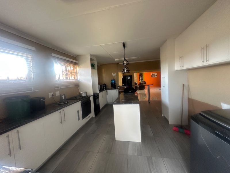 A functional kitchen featuring white cabinetry, a central island with stone countertops, built-in oven, and tiled flooring, offering a clean layout for culinary activities.