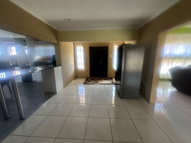 Open plan living area featuring tiled flooring, a central kitchen island, and direct access to the main entrance with security gate.