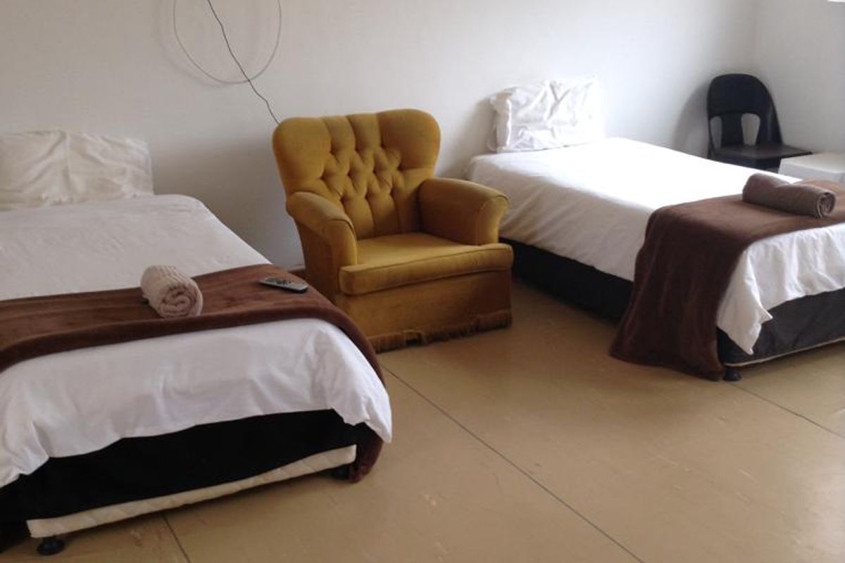 A bedroom featuring basic finishes, currently configured with multiple beds and a seating area.