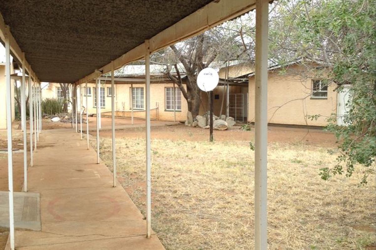 A covered outdoor walkway leading along the rear of the property, featuring concrete paving and views of the garden area.