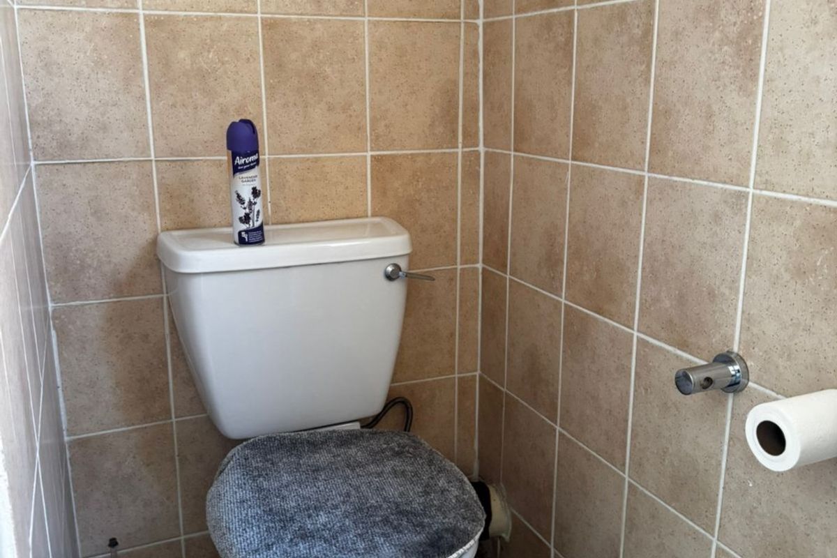 A compact bathroom featuring floor-to-ceiling ceramic wall tiling and a standard toilet fixture.