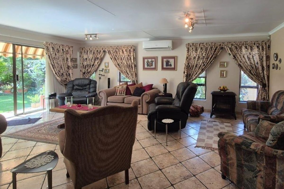 Spacious living room featuring tiled flooring, split-system air conditioning, and large sliding glass doors providing direct access to the garden area.