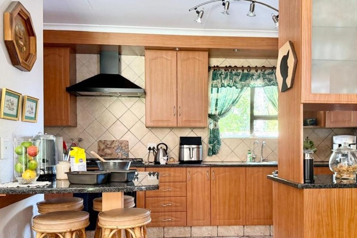 A functional kitchen featuring wooden cabinetry, granite countertops, a tiled backsplash, and an integrated extractor fan, offering a classic and practical workspace.