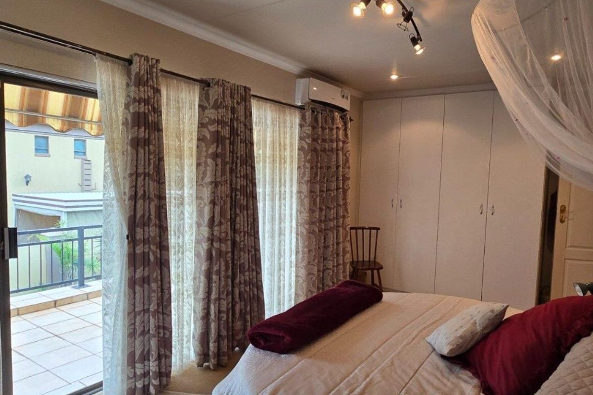 Spacious bedroom featuring built-in cupboards, split-system air conditioning, and direct access to a private balcony through sliding glass doors.