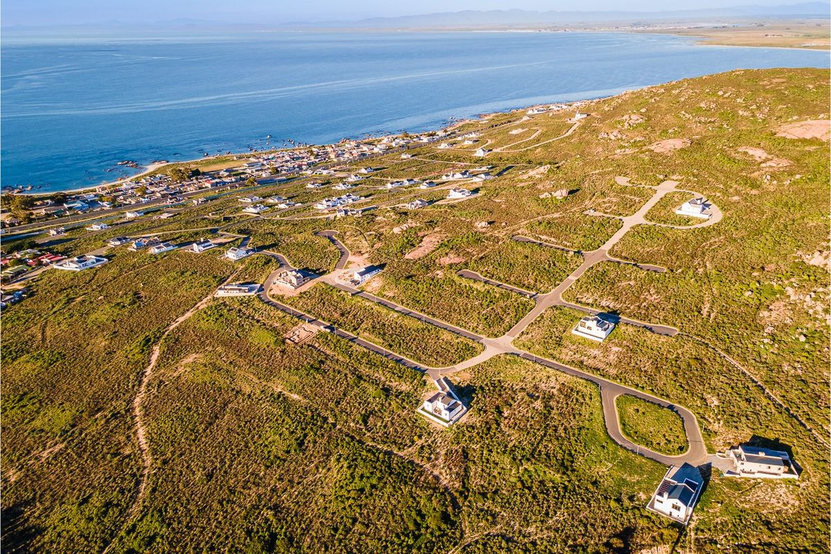 Aerial view of a coastal residential development featuring established road infrastructure and scattered residential properties overlooking the ocean.