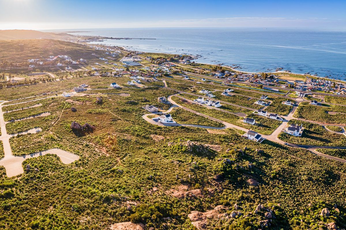 An aerial view of a coastal residential development featuring paved roads and established plots overlooking the ocean.
